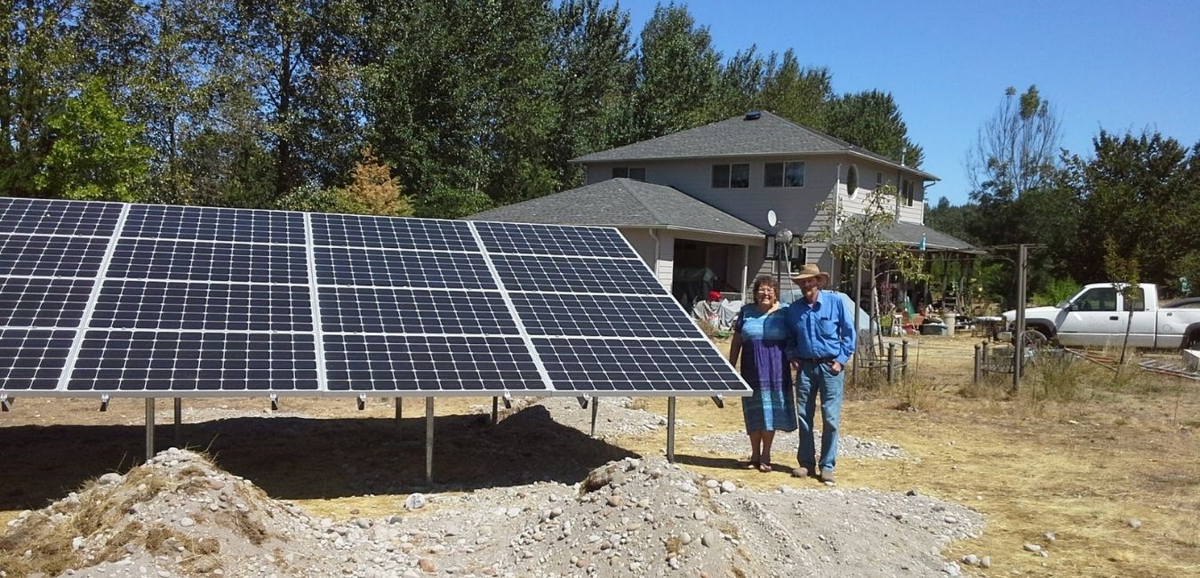 happy couple standing next to new solar panel system in Battle Ground, Wa