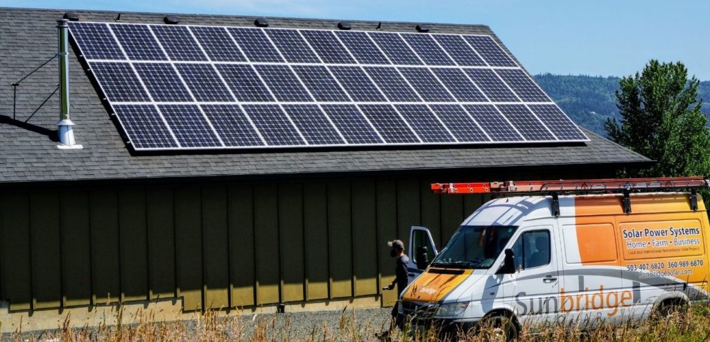 sunbridge truck and installer walking next to a solar system on an Oregon barn