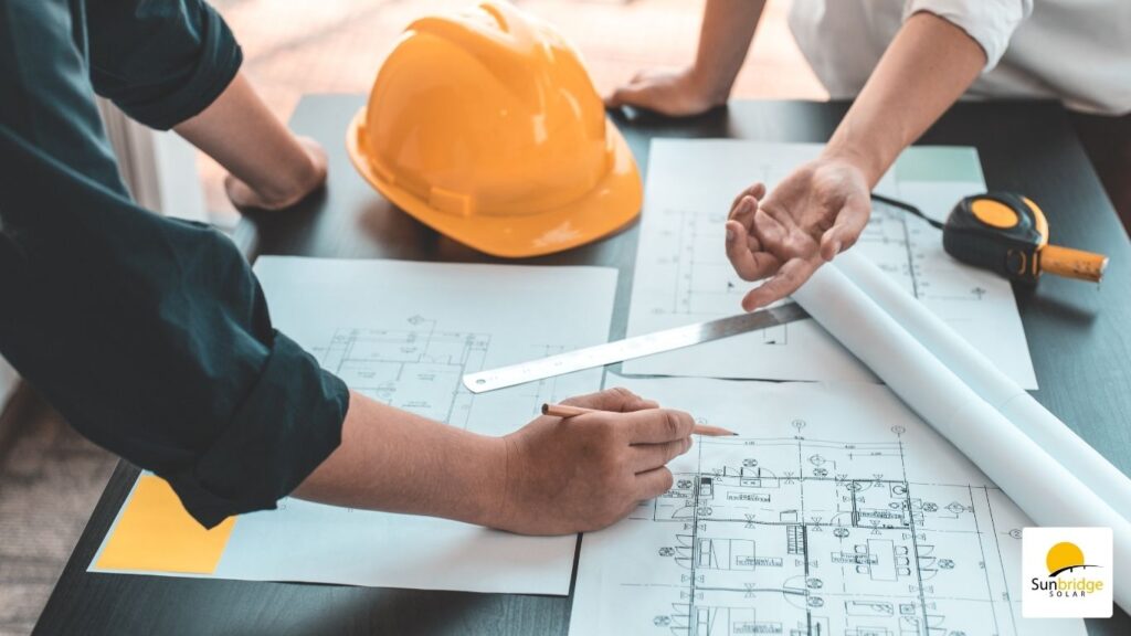 two solar installers reviewing solar plans on plans on a table